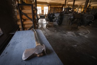 Hatchet on a table, factory hall with historical machines for the production of cardboard and