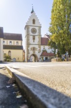 A historic tower with clock in a sunny street, surrounded by trees in autumn, Überlingen, Lake