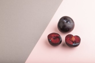 Purple Plum Cut in half on pink and gray pastel paper background. Side view, copy space. healthy