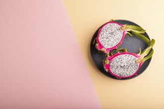 Ripe Pitaya on blue plate on pink and orange pastel paper background, top view, flat lay, copy