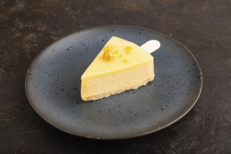 Yellow Cake pop with sprinkles on blue ceramic plate on black concrete background, side view, close