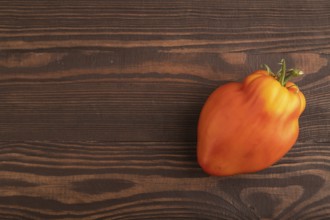 Red Heart Shape tomato on brown wooden background. Top view, flat lay, copy space. healthy food,
