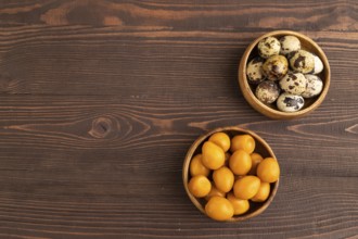 Pile of Smoked Quail eggs in bowl on a brown wooden background. top view, flat lay, copy space