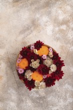Wooden bowl with carrot slices and red Chrysanthemum flowers, Astrantia flowers, flower salad on