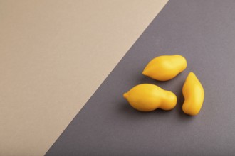 Yellow tomatoes on beige and gray pastel paper background. Side view, copy space. healthy food,