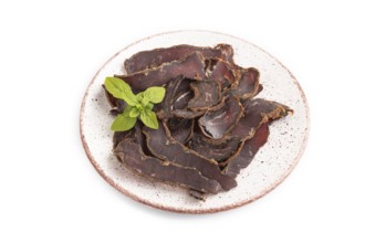 Armenian Basturma dried meat on plate with pepper and herbs isolated on white background. Side view