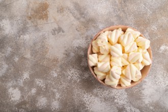 Orange and pink marshmallow in ceramic bowl on brown concrete background, top view, flat lay, copy