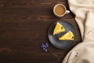 Lemon cake on brown wooden background and linen textile, cup of coffee, top view, flat lay, copy