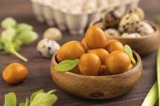 Pile of Smoked Quail eggs in bowl on a brown wooden background. side view, close up, selective