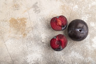 Purple Plum Cut in half on brown concrete background. Top view, flat lay, copy space. healthy food,