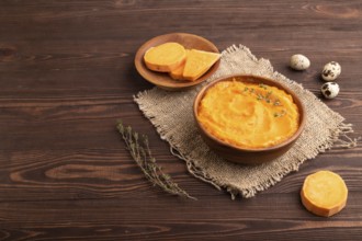Sweet potato porridge in wooden bowl on wooden background and linen textile. Diet, healthy eating
