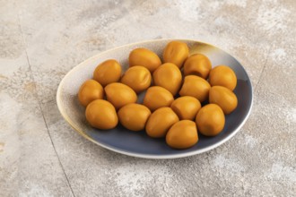 Pile of Smoked Quail eggs on plate on a brown concrete background. side view, close up