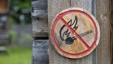 Brennendes Streichholz, kleine runde Holztafel mit aufgemaltem Verbotssymbol gegen das Entfachen