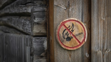 Runde Holztafel mit aufgemaltem Verbotssymbol gegen das Entfachen von Feuer, historischer Bauernhof
