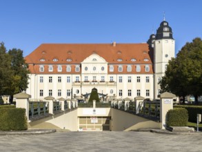 Fleesensee Castle (hotel) with red saddle roof and striking tower under a bright blue sky,