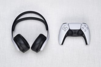 Top shot of a Playstation 5 headset and a game controller on a white Resopal board