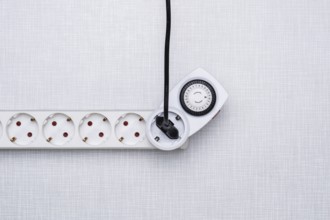 Top shot of a timer in a power strip on a white Resopal panel