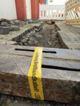 Flapping tape with the indication of an installed fibre optic cable at a construction site in