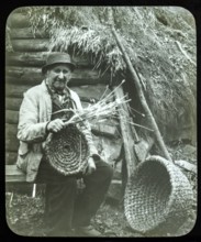 Portrait of elderly countryman weaving straw baskets in England, c 1890s-1900