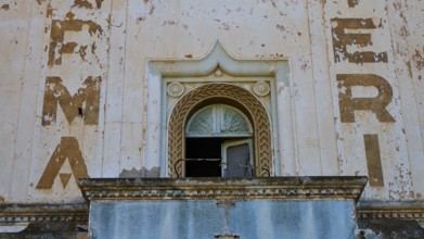 Lost Place, Nahaufnahme der Fassade mit Bröckelstellen und verblassten Schriftzügen über einem