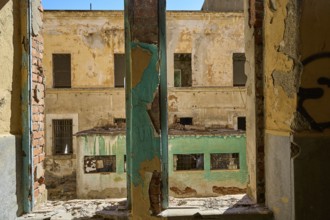Lost Place, Aussicht auf verfallenes Gebäude mit abblätternder Farbe vom Fenster eines
