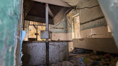 Lost Place, Verlassener Raum mit verfallenen Wänden, rostigen Elementen und Trümmern auf dem Boden,