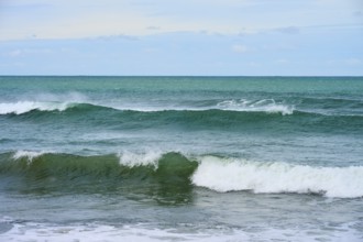Türkisblaues Meer mit gleichmäßigen Wellen unter bewölktem Horizont, Kaka Point, Clutha District,