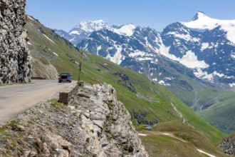 View of alpine road carved into rocky escarpment in high Alps near pass summit of highest asphalted