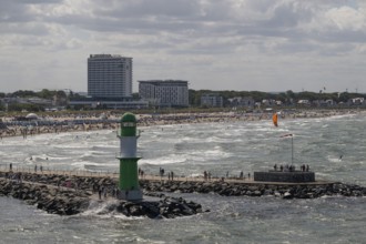 Green and white lighthouse, pier light Westmole in front of lively beach and hotels in the