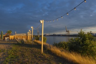 View from the outside area of a restaurant at Lankenauer Höft through a string of lights onto