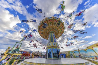 Chain carousel in motion in front of a white-blue sky, Theresienwiese, Oktoberfest, Munich, Upper