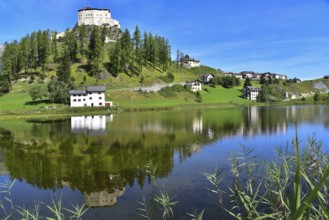 Tarasp Castle in the Lower Engadine is reflected in Lake Tarasp, Graubünden, Switzerland