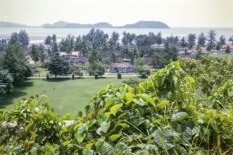 View to offshore island over houses in coastal area near Mersing, Johor, Malaya, Malaysia, south