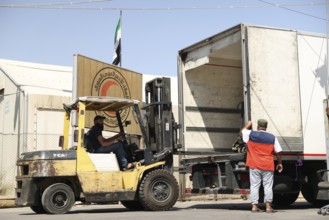 Relief workers unload boxes of medical aid provided by Qatar at Damascus International Airport,