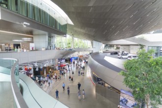 Large, modern showroom with visitors and various cars, BMW Welt, Munich, Germany