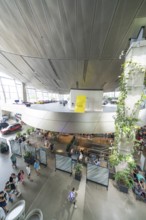 View from above of a modern room with plants and people under a yellow accent, BMW Welt, Munich,