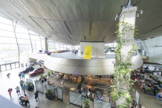 Aerial view of a modern interior with a wall of plants and a crowd of people, BMW Welt, Munich,
