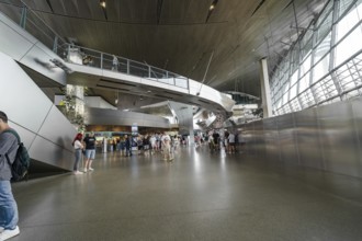 Large interior with modern architecture and people walking through the space, BMW Welt, Munich,