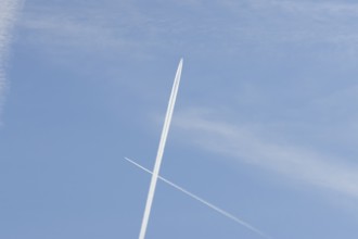 Two jet passenger aircraft with vapour trails or contrails flying in a blue sky crossing making a