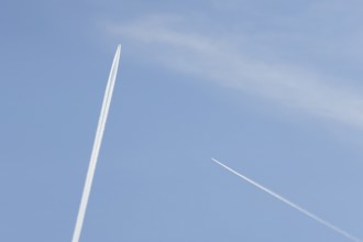 Two jet passenger aircraft with vapour trails or contrails flying in a blue sky, England, United