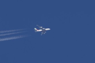 Airbus A380 jet passenger aircraft of Emirates airlines with a vapour trail or contrail flying in a