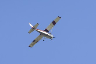 Reims Cessna F172M Skyhawk light aircraft flying in a blue sky, England, United Kingdom