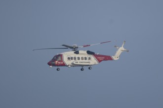 Sikorsky S-92A helicopter of the UK HM Coastguard flying in a blue sky, England, United Kingdom
