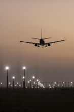 Boeing 737 jet passenger aircraft of Ryanair airlines landing over runway lights at sunset, London