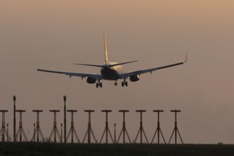 Boeing 737 jet passenger aircraft of Ryanair airlines landing over runway lights at sunset, London