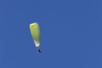 Paraglider flying in a blue sky, England, United Kingdom