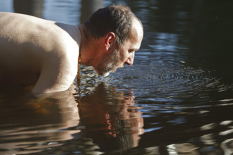 Man in the water during body care while travelling, Müritz National Park, Mecklenburg-Western