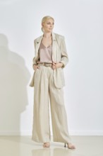 A model showcases a stylish light-colored suit paired with a silk top in a contemporary indoor