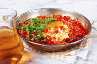 Traditional Turkish dish, scrambled eggs with tomatoes, Menemen, with herbs, in a frying pan,