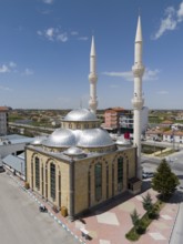 Modern mosque with two high minarets and several domes in an urban setting, aerial view, Mevlana